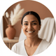Close-up portrait of a happy South Asian woman smiling, with a warm cream and terracotta background.